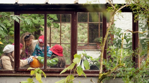 A woman and three children looking at pumpkins inside a greenhouse at Rowallane, County Down.